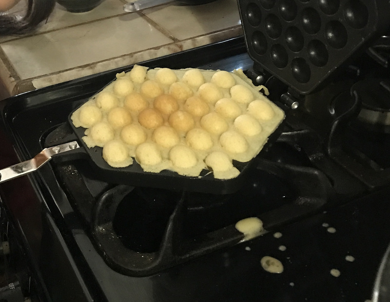 Bubble waffle maker with cooked waffle on top of gas stove